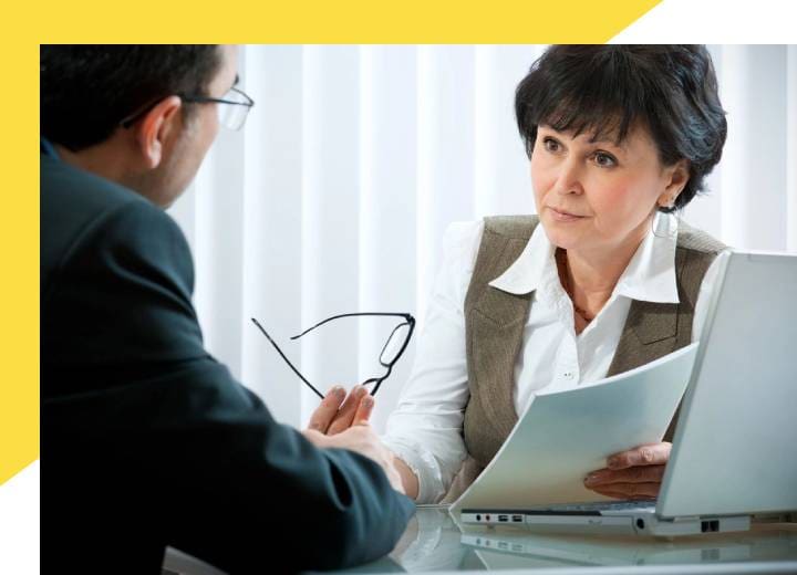 A woman is holding an open book while talking to another person.