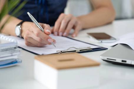 A person writing on paper with a pen.